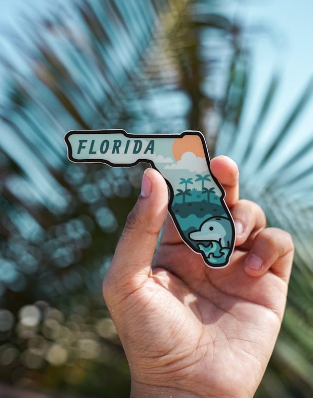 A hand holding a souvenir shaped like the state of Florida, USA.